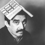 A black and white photo of a man with a book on his head
