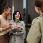 Three girls holding wine glasses and talking to each other