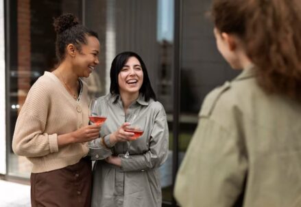 Three girls holding wine glasses and talking to each other