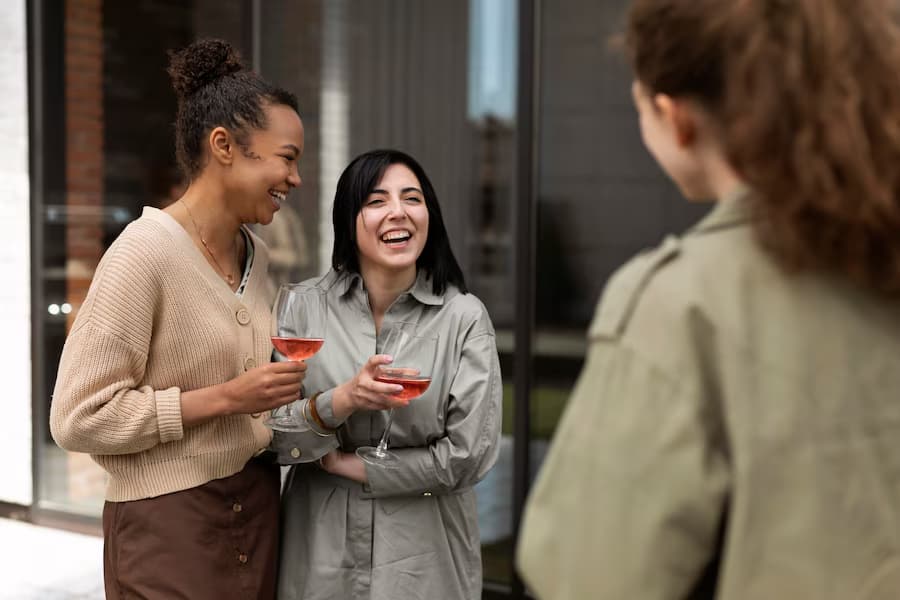 Three girls holding wine glasses and talking to each other